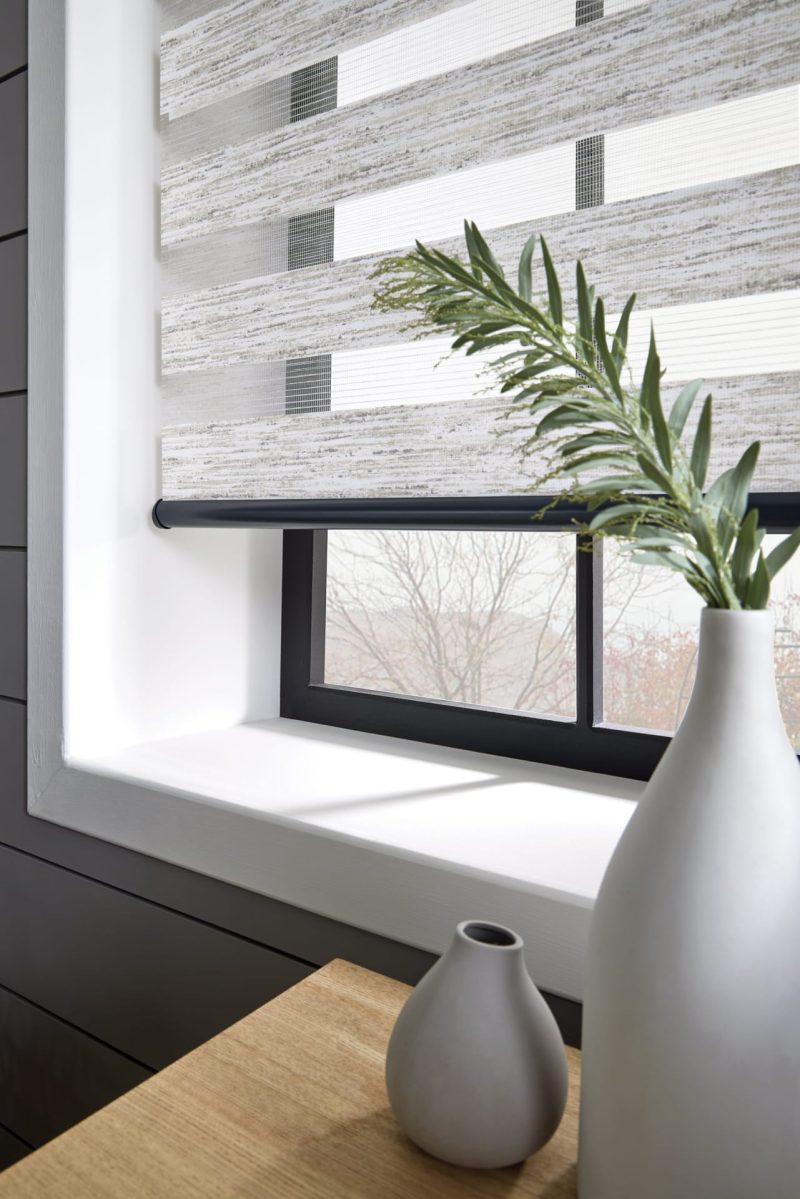 Decorative grey vases on a table against a window fitted with patterned light grey vision blinds in Rochester